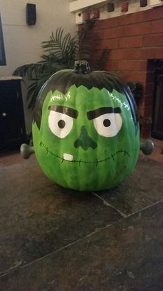 a large green pumpkin with a face painted on it's side sitting on top of a table