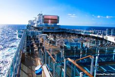 the deck of a cruise ship with lots of glass railings and blue water in the background