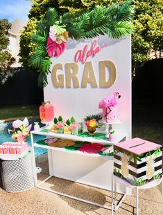 a table that has some cakes on it and flowers in the grass near a pool