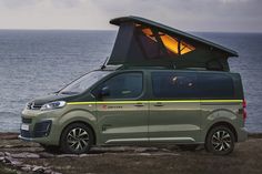 a van parked on the side of a cliff by the ocean with its roof open