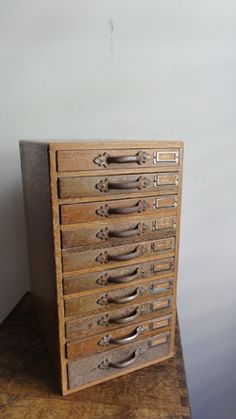 a wooden file cabinet sitting on top of a table next to a wall with white walls