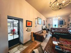 a living room filled with lots of furniture and pictures on the wall next to an open door