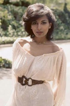 a woman standing in the street with her hand on her hip and wearing a belt around her waist