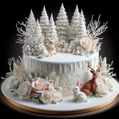 a cake decorated with white frosting and flowers on top of a wooden table next to two deer figurines