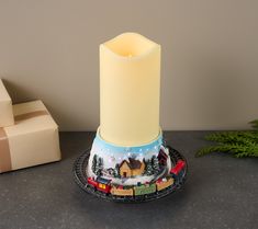 a lit candle sitting on top of a plate next to a christmas tree and presents