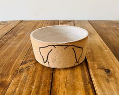 a bowl with an elephant drawn on it sitting on a wooden table next to a wall