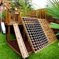 an image of a wooden play set in the grass with a slide and climbing frame