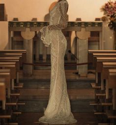 a woman in a white dress standing in front of pews with her hands on her hips