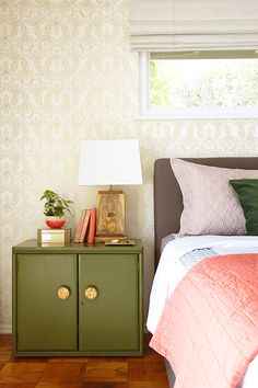 a bedroom with a bed, nightstand and lamp on the side table in front of it