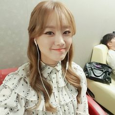 a woman sitting in a chair with ear buds on her ears and smiling at the camera