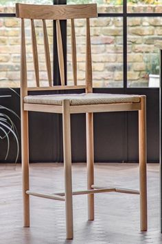 a wooden chair sitting on top of a hard wood floor next to a brick wall