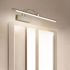 a bathroom light that is on above a sink in a room with white walls and flooring