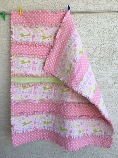 a pink and white quilt hanging on a clothes line with pegs in front of it