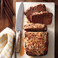 slices of meatloaf on a cutting board next to a knife and some cinnamon sticks