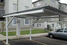 an empty parking lot with cars parked in front of the building and apartment buildings behind it