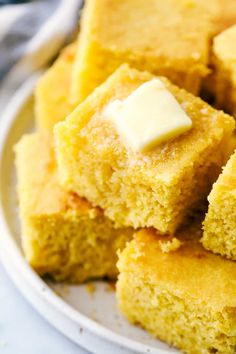 several pieces of cornbread on a plate with butter cubes in the middle and one bite taken out