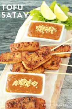 grilled chicken skewers with sauce and garnishes on a tray