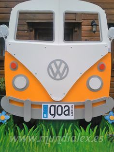 an orange and white vw bus parked in the grass