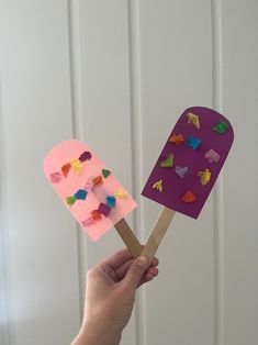 a hand holding two popsicles made out of construction paper