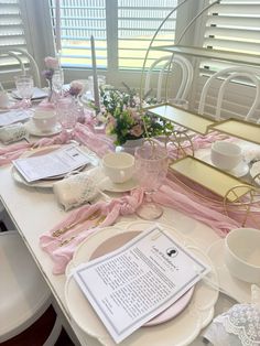 the table is set with pink and white dishes, cups, and napkins on it