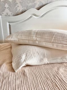 two pillows are stacked on top of each other in front of a white headboard