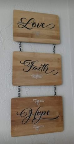 three wooden signs that say love, faith and hope hanging on a wall in a room