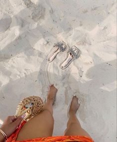 a woman's feet in the sand with sandals and rings on her toes, wearing an orange skirt