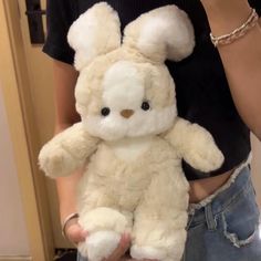 a person holding a white stuffed animal in their hands