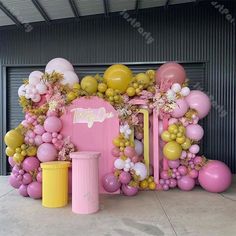 a pink and yellow birthday decoration with balloons