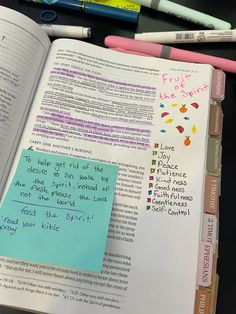 an open book with writing on it next to markers and pencils in front of it