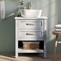 a white sink sitting on top of a bathroom vanity next to a wooden table and chair