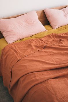 the bed is made up with orange sheets and pink pillowcases on top of it