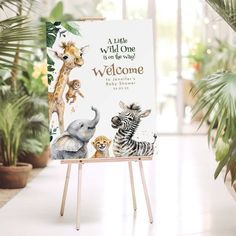 an easel with a welcome sign in front of potted plants