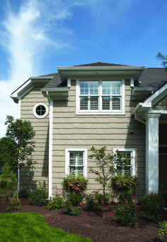 a house that has some plants in front of it and bushes around the outside corner