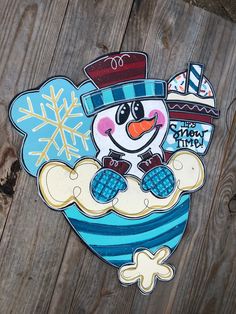 a snowman with a hat and scarf on it's head is standing in front of a wooden fence