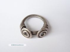 a silver ring with two spirals on the outside and inside, sitting on a white surface