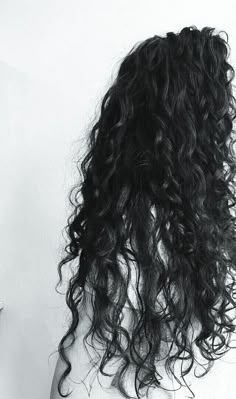 the back of a woman's head with long curly hair in black and white