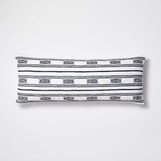 a black and white striped pillow on a white background with an arrow design in the middle