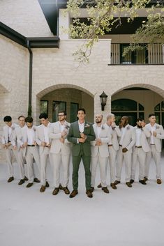 a man standing in front of a group of men wearing white suits and ties with their arms around each other