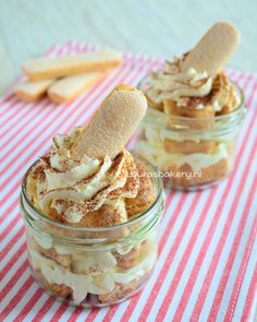 two jars filled with desserts sitting on top of a red and white table cloth