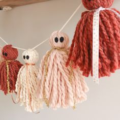 several knitted toys hanging from a line on a string with white and red yarn