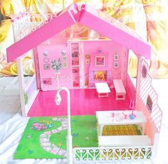 a pink doll house with furniture and accessories on the floor in front of a bed