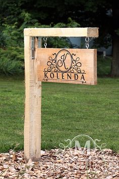 a wooden sign that says kolenda hanging from it's side in the grass