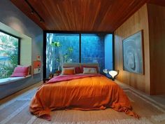 an orange bed in a bedroom next to large windows