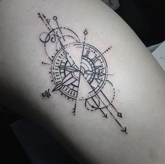 a black and white photo of a compass tattoo on the back of a woman's thigh