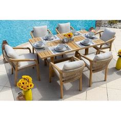 an outdoor dining set with sunflowers and plates on the table next to a swimming pool