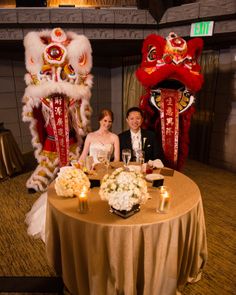 a man and woman sitting at a table in front of two lions