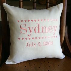 a personalized pillow on a chair with the name sydney written in pink and hearts