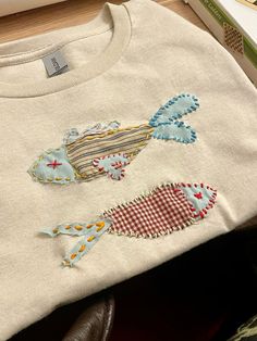 a white sweater with colorful fish appliqued on it