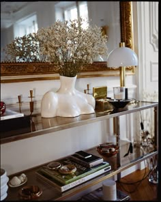 a vase with flowers sitting on top of a glass shelf in front of a mirror